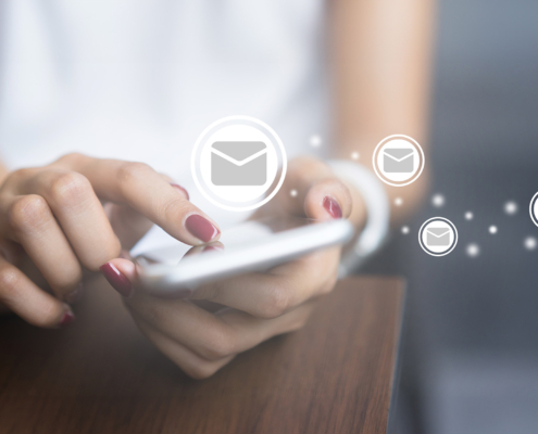 Front view of a woman holding a phone with email graphics overlayed