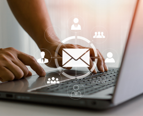 Side view of someone typing on laptop with email graphics overlayed