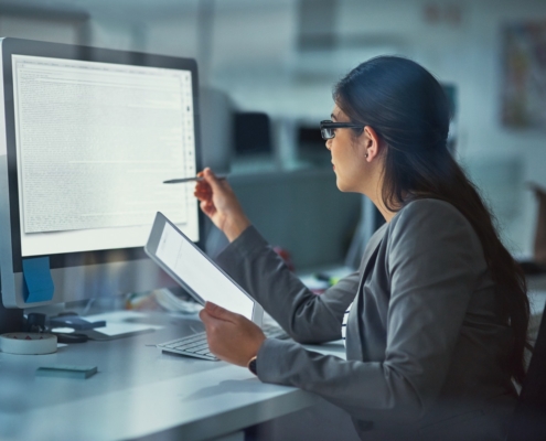 Computer screen, night and web development with woman at desk in office for coding or programming